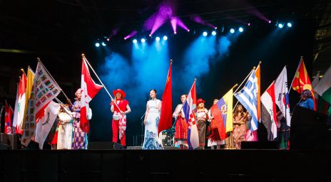 People on stage holding different national flags