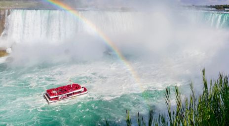 La croisière en bateau Hornblower sur l’eau, près de Niagara Falls avec un arc-en-ciel brillant au-dessus