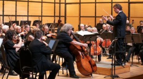 L’Orchestre symphonique de Toronto se produit sur scène avec un chef d’orchestre dirigeant et des musiciens jouant des instruments à cordes, y compris des violoncelles et des violons.