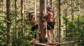 A couple on an elevated platform getting ready to zipline at Treetop Trekking.