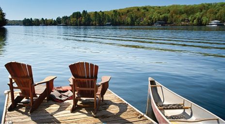Two Muskoka chairs on a dock on the lake